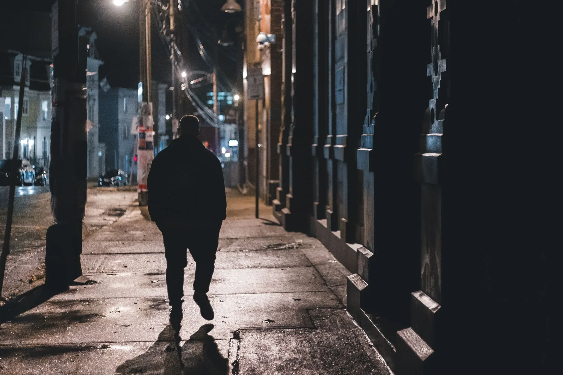 Someone walking home alone down a city street at night