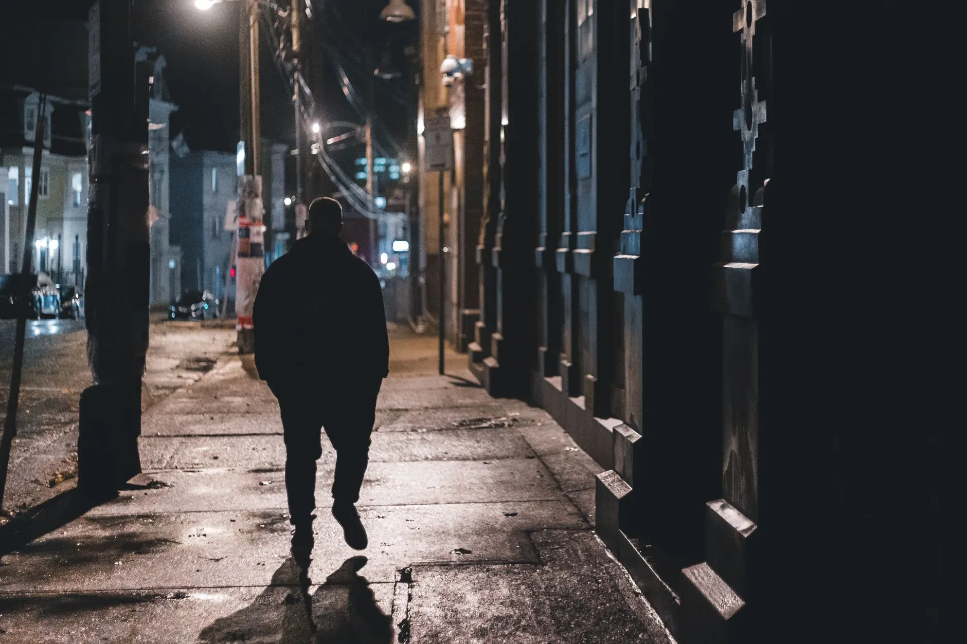 Someone walking home alone down a city street at night